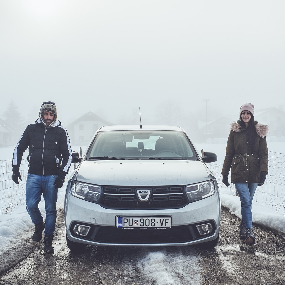 A couple near a car in the snow