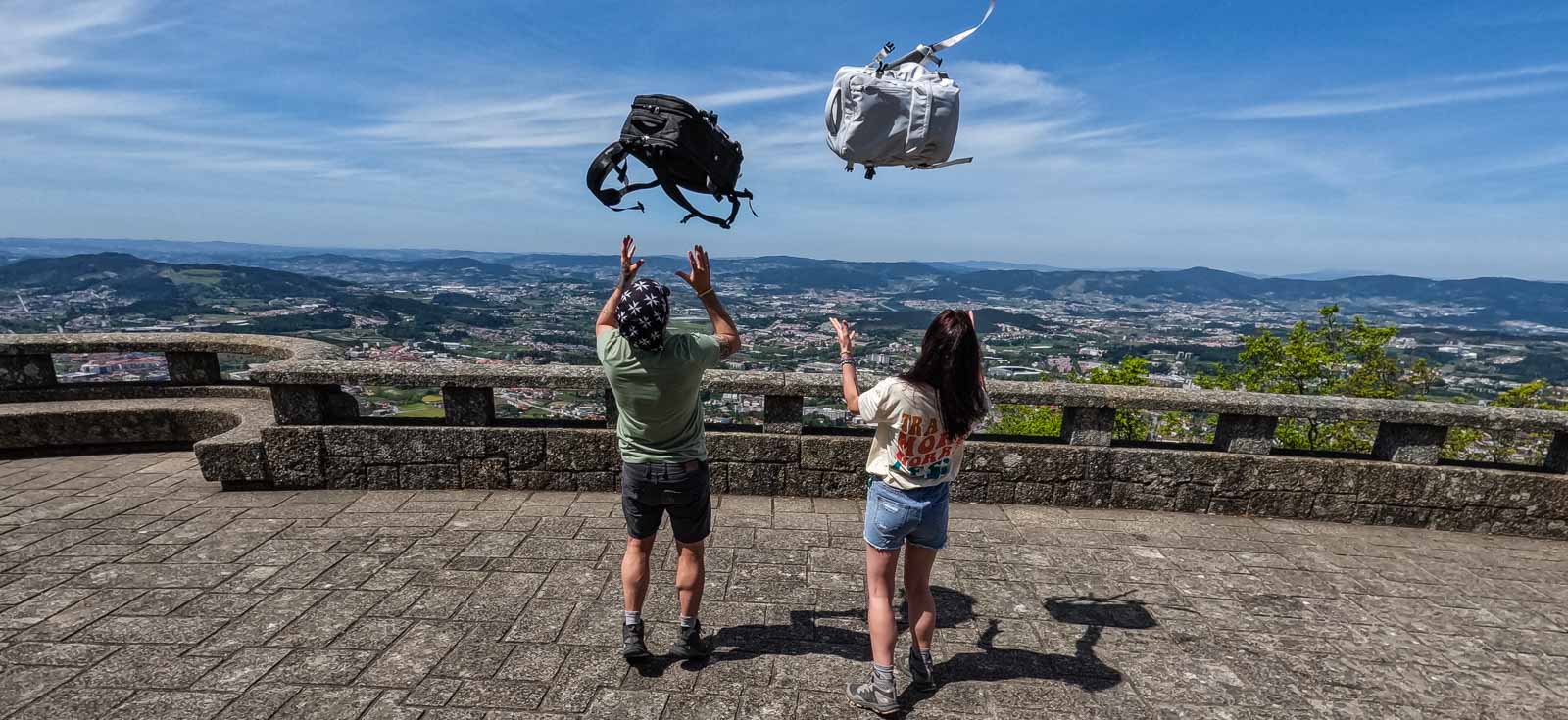 Couple throwing backpacks in the air - Portugal Travel Guide